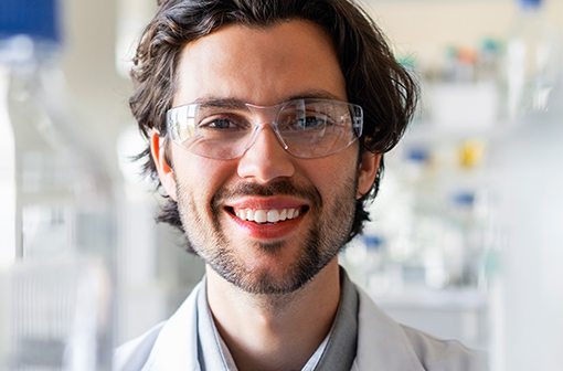 East_Coast_Website_Image Happy male scientist wearing protective eyewear