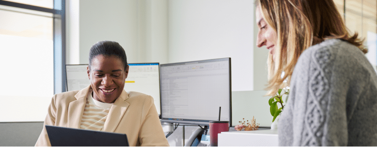 Two employees looking at computer screen at a desk