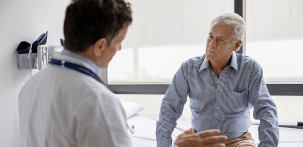 Male doctor talking to male patient sitting on exam table