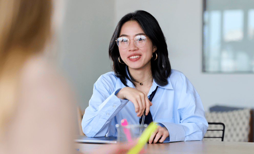 Women with glasses smiling at a desk