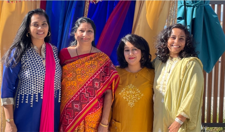 Four women in saris smiling for camera