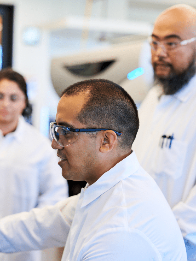 Three oncology scientists working together in a lab on a screen