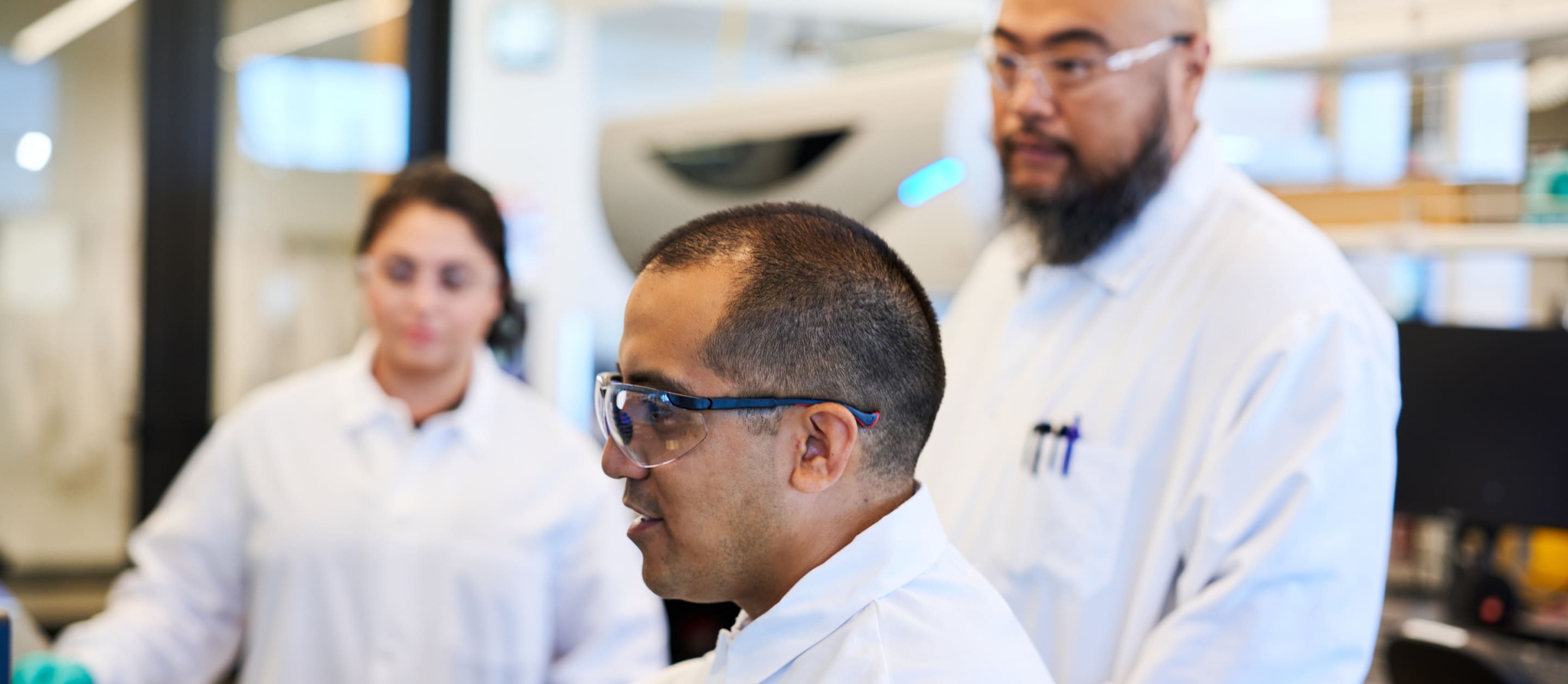 Three oncology scientists working together in a lab on a screen