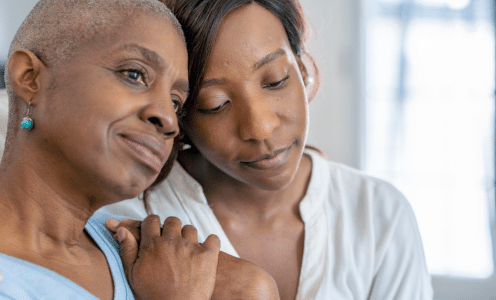 Two women hugging and looking away from camera