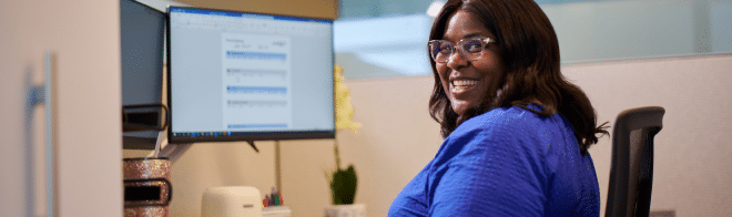 Woman sitting in front of computer smiling at camera