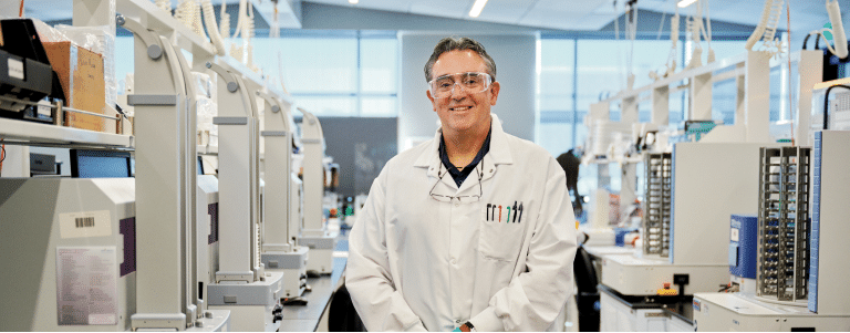 Scientist standing in lab smiling at camera