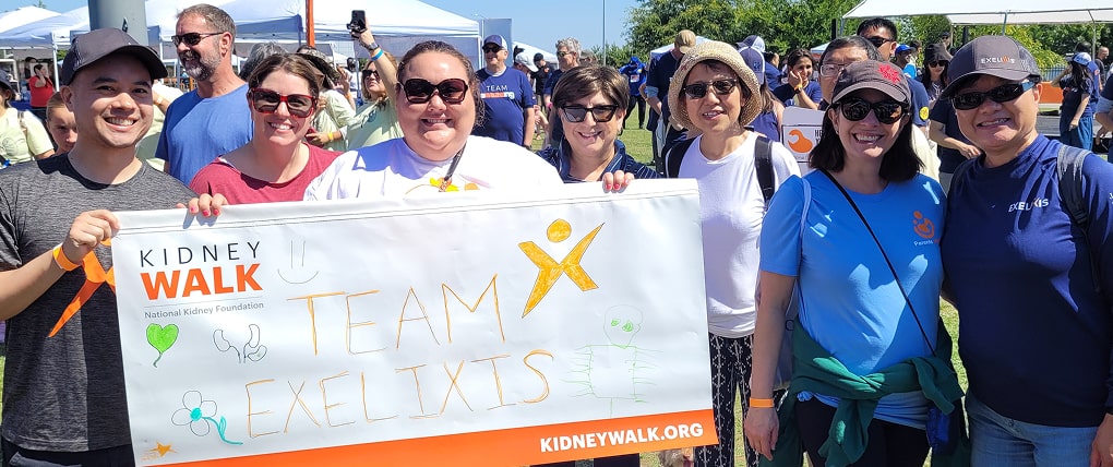 Team Exelixis volunteers holding a Kidney Walk banner at an outdoor charity event.